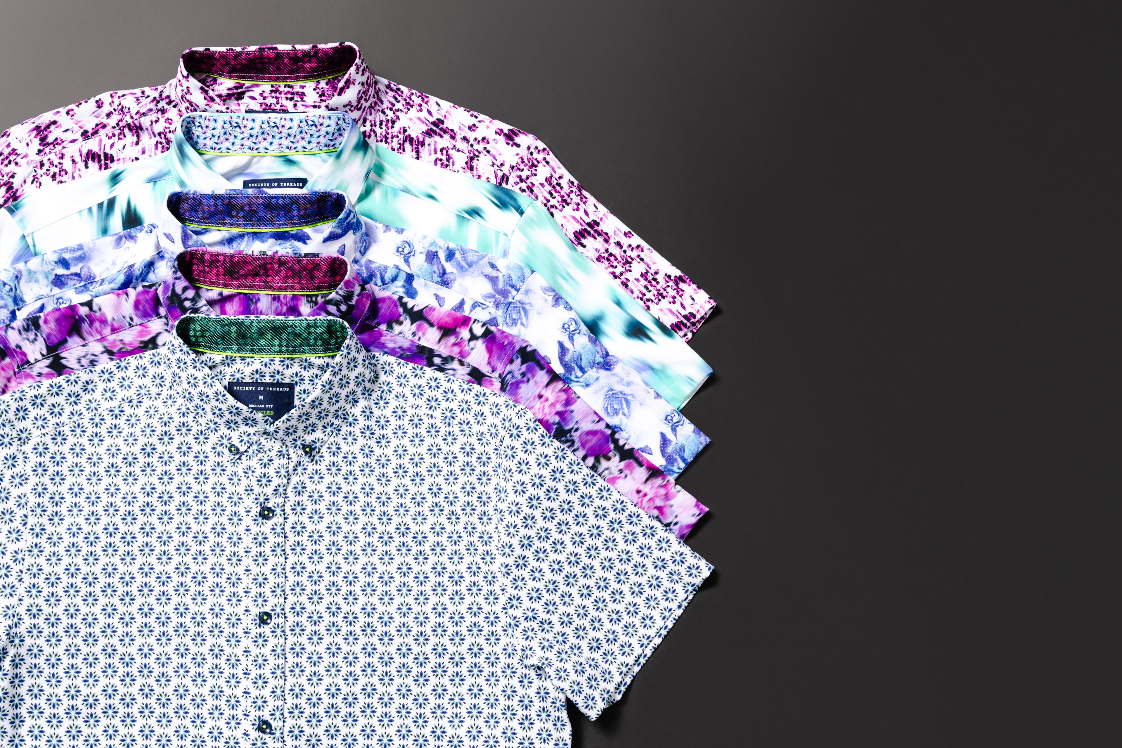 Five patterned shirts stacked on a dark background