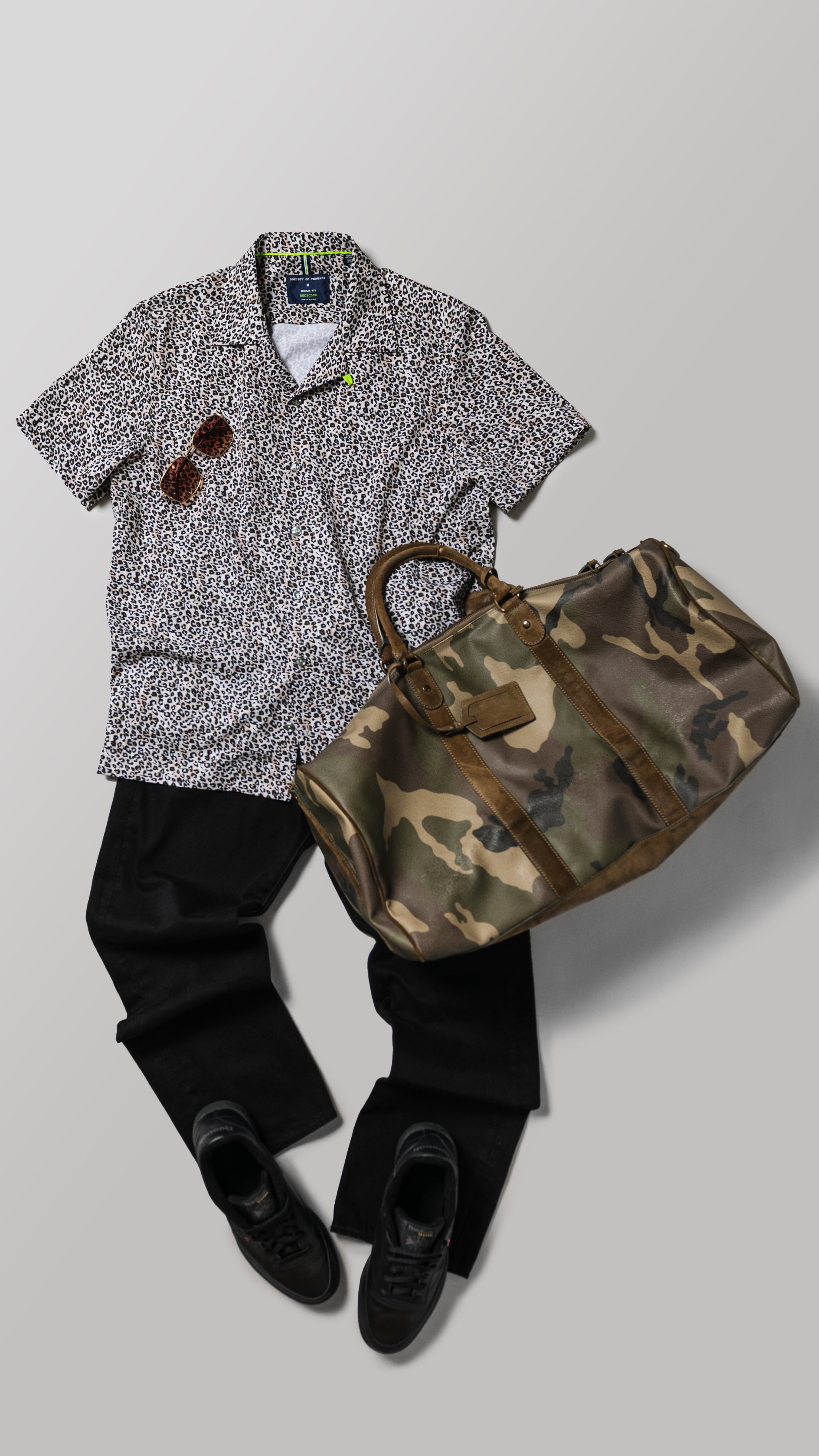 Shirt, pants, shoes, and camouflage bag arranged on a light gray background